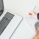 Seorang penulis mencatat ide di depan laptop